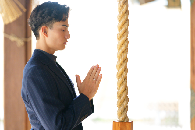 神社でお参りする男性